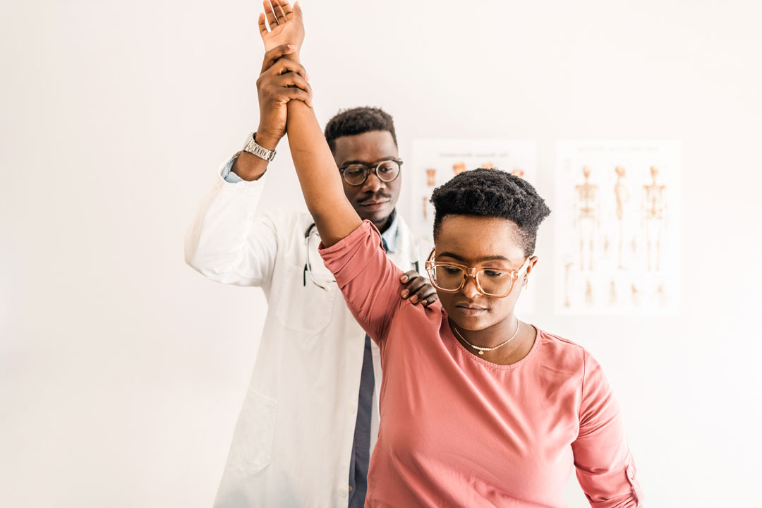 Doctor checking woman's shoulder reflexes