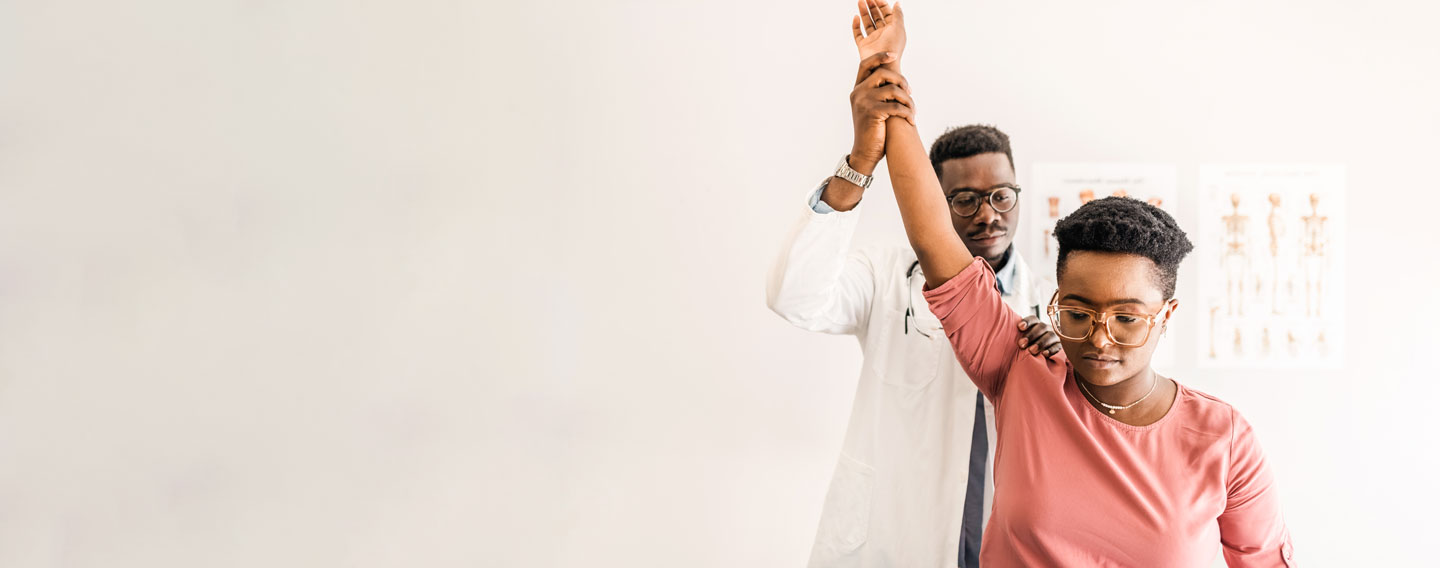 Doctor checking woman's shoulder reflexes